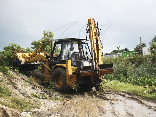 Anthony Minott/Freelance Photographer
A tractor dumps debris, beside a main drain in Greater Portmore, that seperates Greater Portmore High from the Primary school during the effects of Hurricane Sandy in Portmore, St Catherine last Thursday.