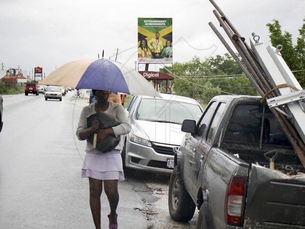 Anthony Minott/Freelance Photographer
A woman shelters from the rain in Braeton after the passage of Hurricane Sandy in Portmore, St Catherine last Thursday.