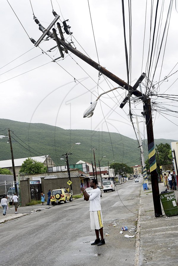 Ian Allen/Photographer
Despite the obvious danger, this man stop under the broken utility pole to take a photograph along Windward road in Kingston. The pole was broken during the passage of Hurricane Sanday.