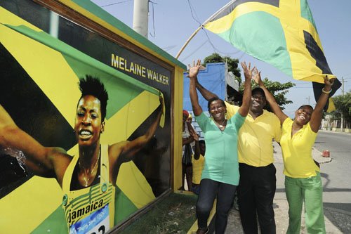 Norman Grindley/Chief Photographer
As Melaine Walker took home the silver in the women's 400m hurdles in Daegu, South Korea, yesterday family members celebrated beside her mural on Maxfield Avenue in St Andrew. From left are Melaine's mother Jenefer Wilson; her father Japheth; and sister Natalie.
