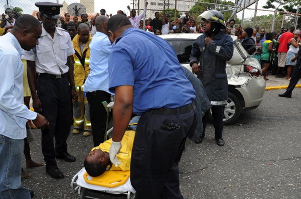 Norman Grindley /Chief Photographer
Ambulance workers remove Shane Allen, the driver of this Nissan Tiida (background) that collided with a truck driven by Stacy Kennedy, at the intersection of East and North Street in downtown Kingston yesterday evening.