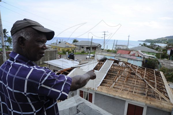 Ricardo Makyn/Staff Photographer 
 Desmond Patterson poinst to the Roof of His Home  in Long Bay Portland that was taken off by the winds associated with Hurricane Sandy