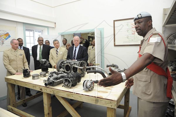 Ian Allen/Photographer
Sergeant Howard Farquharson right, explains the use of the different parts to assemble a helicopter engine to  Dignitaries duirng a tour of the Jamaica Military Aviation School.  Occasion was a ceremony for the Renaming of the Jamaica Military Aviation School and Opening of the Department of Aircraft Technician Training at the Jamaica Defence Force Air Wing at the Norman Manley Airport.