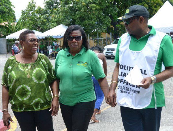 Ian Allen/Staff Photographer
Edmond Bartlet right and Olivia Grange left escort Beverly Prince centre to the Polling Station at the Half Way Tree Primary School to vote during the Cassia Park Division Bi-Election on Thursday.