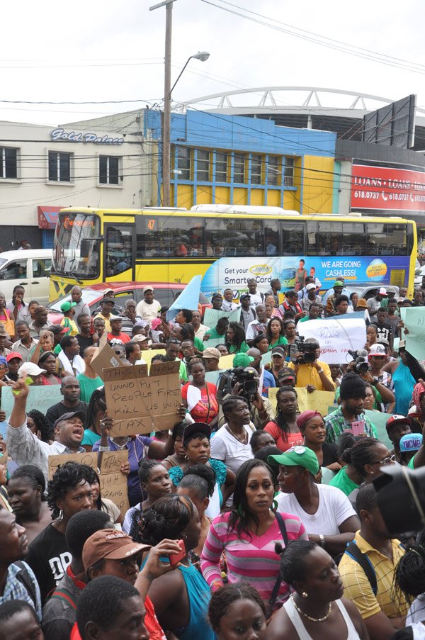 Jermaine Barnaby/Photographer
A JUTC bus passes with passengers aboard as protestors protest against bus fare increase in Half way Tree on Monday August 25, 2014.
