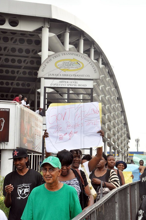 Jermaine Barnaby/Photographer
Persons marching pass the Transport Center in Half Way Tree as they carried out protest action against bus fare increase in  on Monday August 25, 2014.