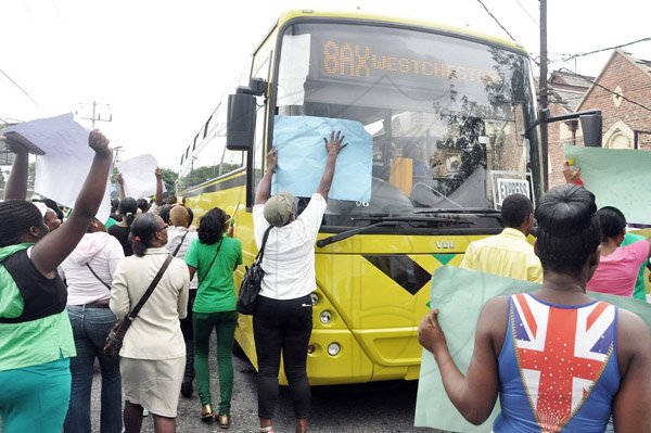 Jermaine Barnaby/Photographer
Persons block the path of a JUTC bus in Half Way Tree as they carried out a march down towards the NWA corporate office on Maxfield Avenue  against bus fare increase on Monday August 25, 2014.