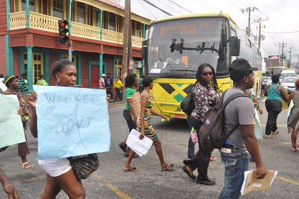 Jermaine Barnaby/Photographer
Protestors marching up Half Way Tree infront a JUTC bus where they staged a peaceful demonstration against bus fare increase in Half way Tree on Monday August 25, 2014.
