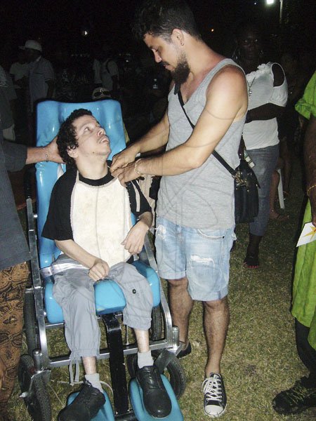 Paul Williams/Gleaner Writer
Calabash
Film-maker Storm Saulter attends to his brother, Astro, who is afflicted with cerebral palsy, just after the showing of a short film, 'Morning Star', on Saturday evening, May 26, at Calabash Literary Festival, Treasure Beach, St Elizabeth. Morning Star is about how Astro uses computer technology to create works of art.
