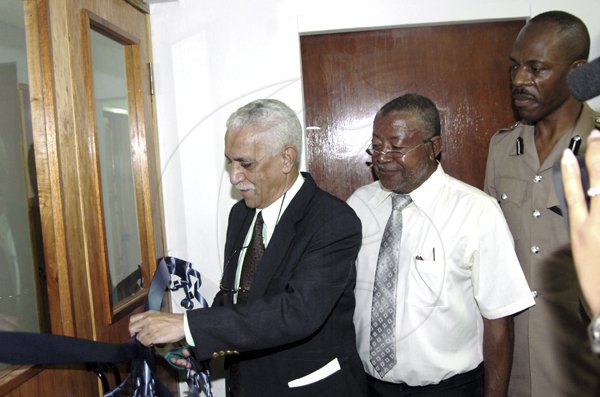 Norman Grindley /Deputy Chief Photographer
Senator Col. Trevor MacMillan (left) cuts the ribbon to enter the new Annex building at Constant Spring police station in St. Andrew yesterday. Also in photo are Ken Cole (centre) a civil engineer and Assistant Commissioner of police Carl Williams in charge of Area 5 police divison.