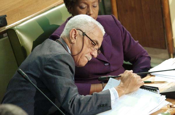 Rudolph Brown/Chief Photographer
Colonel Trevor MacMillan leafs through Ministry papers after being sworn-in yesterday as an Opposition Senator in the Upper House of Parliament. Senator Prudence Kidd-Deans looks on.