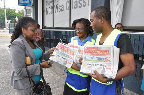 Jermaine Barnaby/Photographer
Rudolph Speid (right) group Finance & Procurement and Shena Stubbs-Gibson (center) Company Secretary/ Senior Legal Advisor both jointly sell a copy of The Gleaner along Knustford Boulevard during the Gleaner's corporate street sale day on Monday September 8, 2014.