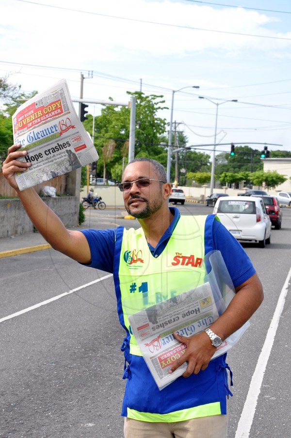 Jermaine Barnaby/Photographer
Managing director of The Gleaner Christopher Barnes holds aloft a copy of the newspaper in a bid to sell oncoming motorist during his company's corporate street sale day on Monday September 8, 2014 along Kings House road.