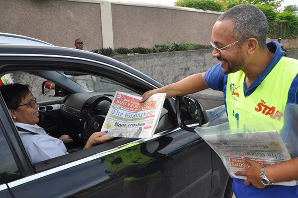 Jermaine Barnaby/Photographer
Managing director of The Gleaner Christopher Barnes (right) is pleased as he sold a copy of the newspaper to a motorist along Kings House road during the company's corporate street sale day on Monday September 8, 2014.