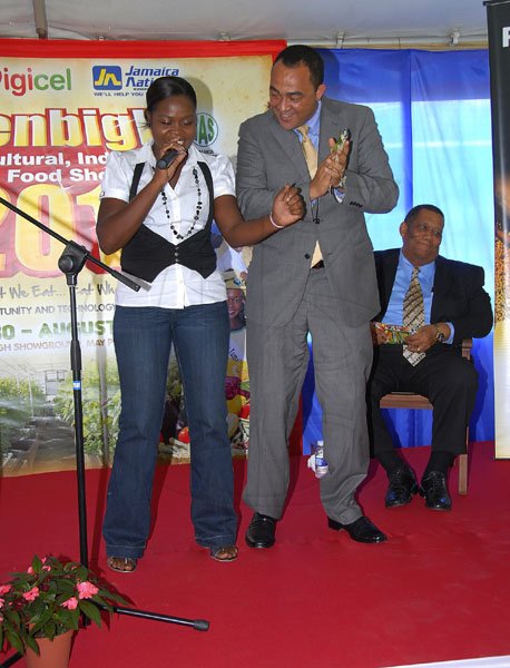 Farmers urged to learn  how to maximise technology (JIS story)                                                                                                                                                                                       Minister of Agriculture and Fisheries, Hon. Dr. Christopher Tufton (right), joins 2008 Digicel Rising Stars winner, Camille Davis on stage, as she entertains the audience at the launch of the Denbigh Agri-Industrial and Food Show 2011, held on the lawns of the Ace Supercentre, White Marl, St. Catherine, on June 21.  Seated at right is the Opposition Spokesman on Agriculture, Roger Clarke.