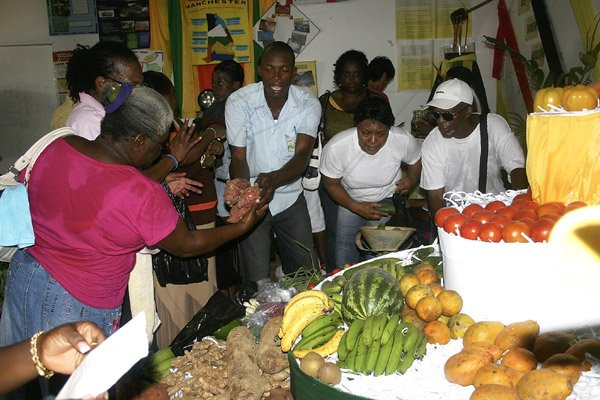 Photo by Christopher Serju
Robert Townsend (centre) extension officer with the Rural Agricultural Development Authority  in Manchester is hard pressed to meet the demand for produce from the parish pavilion which was ajudged the top display at Denbigh Agricultural and Industrial Show in Clarendon yesterday.