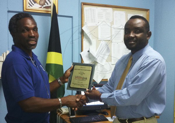 Contributed 
ichael Ellis (right), the principal of Green Pond High School, in St. James, accepts a Gleaner 'Youth Link Plaque' on behalf of his school from Adrian Frater, the News Editor at the Gleaner's Western Bureau.
                                               - Diana Frater: Photo