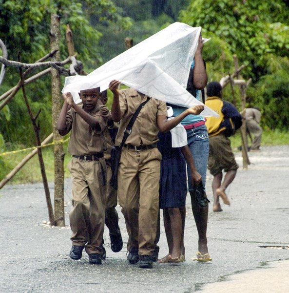 Ricardo Makyn/Staff Photographer
Students use a piece of plastic to protect themselves from heavy rains as they make their way from school in Landewey, St Thomas yesterday.