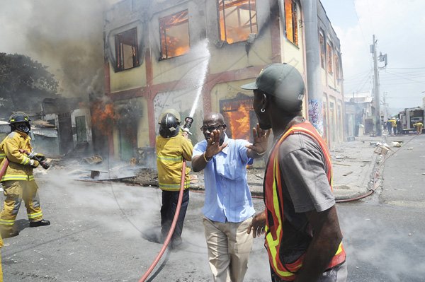 Norman Grindley/Chief Photographer
Desmond McKenzie (left) member of parliament for West Kingston, tries to control an irate resident (right) who wants to instruct fire fighters how to put out a major fire that destroyed several houses on Regent Street in downtown Kingston. Three fire units and a water truck arrived on the scene as fire personnel tried to contain the blaze September 26, 2012.