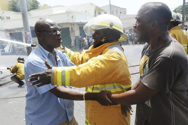 Norman Grindley/Chief Photographer
Desmond McKenzie (left) member of parliament for West Kingston, tries to control an irate resident (right) who wants to instruct fire fighters how to put out a major fire that destroyed several houses on Regent Street in downtown Kingston. Three fire units and a water truck arrived on the scene as fire personnel tried to contain the blaze September 26, 2012.