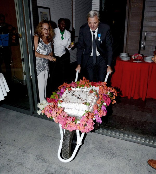 Winston Sill/Freelance Photographer
French Ambassador Ginette de Matha host Reception and Handing over of the  insignia of French National Order of Merit to Etienne Andre`, held at Hillcrest Avenue on Friday night March 14, 2014. Here Andre`, who have a 'thing' for Wheelbarrows, is seen here pushing-in his surprised Wedding Anniversary cake on one.