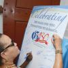 Ricardo Makyn/Staff Photographer 
The Gleaner's only Editor in Chief Wyvolyn Gager signs the 180 board at the exit of the Church at the Gleaner 180  anniversary Church service at the Kingston parish Church on Sunday 31.8.2014