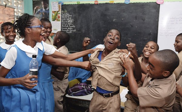 Jermaine Barnaby/Photographer
Courtney Thomas (center) being thugged and shoved as he's being congratulated by classmates for his Jamaica College placement in the Gsat results at the Mountain View Primary school in Kingston on Thursday June 18, 2015.