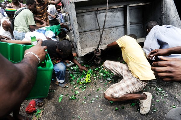 Ricardo Makyn/Staff Photographer.                                 Looters scramble to get their hands on beer bottles in the wreckage of a truck that was transporting Heineken along the Linstead Bypass in St Catherine.