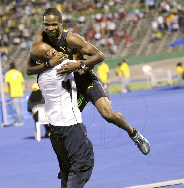 Ricardo Makyn/Staff Photographer
Munro College's Delano Williams jumps into the arms of coach Neil Harrison after winning the Class One boys' 100 metres final at the ISSA/GraceKennedy Boys and Girls' Athletics Championships at the National Stadium last night.