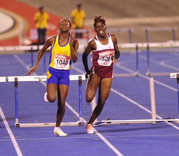 Ricardo Makyn/Staff Photographer
Left Winner Adrianna Brown of St Elizabeth Technical in a close fight with Holmwoods Janeive Russell who is put off by hitting the Hurldes in the  Girls open 400 Meters Hurdles Final   at the Boys and Girls Championships at the National Stadium on Friday 30.3.2012