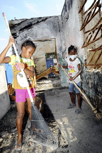 Norman Grindley/Chief Photographer
Seven-year-old Mickailla March (left) and Shadeka Hanson, 10, both members of the Hannah Town Police Youth Club in West Kingston, put in some Labour Day work on their burnt out police station yesterday. Residents turned out to clean debris from the station as they call for the authorities to rebuild the station.