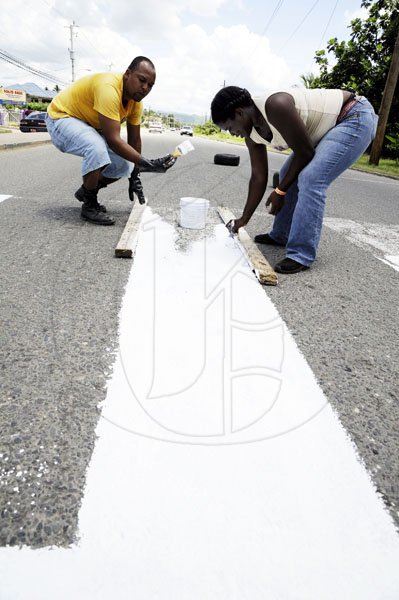 Ricardo Makyn/Staff Photographer
Members of the Little Feet Basic School Parent Teachers Association on Brunswick Avenue in Spanish Town paint the pedestrian crossing adjacent to the school as their Labour Day project yesterday.