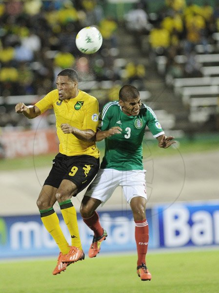 Ricardo Makyn/Staff Photographer                                     Jamaica's Ryan Johnson (left) competes with Mexico's Carlos Salcido for the ball during last night's CONCACAF World Cup qualifier at the National Stadium.  Aldo de Nigris headed in a Salcido cross in the 48th minute to hand Mexico a 1-0 win.