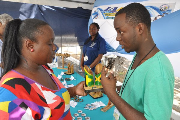 Jermaine Barnaby/Photographer
President of JAEP, at the St Elizabeth High School STETHS Chevaun Burrell (right) shows off one of the pieces done by students at his booth to Sharlene Grant during the Jampreneurs Expo & Summer Jam at the  Ranny Williams Entertainment Centre on  Saturday, July 5, 2014.