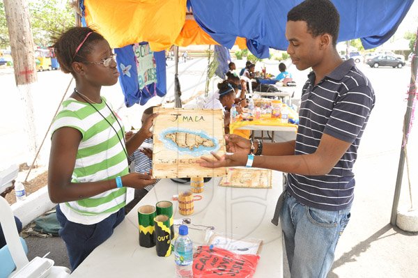 Jermaine Barnaby/Photographer
Nicoya Baugh (left) of the Blings N Things at the Jamaica Christain School For the Deaf explains one of the pieces on display at her booth to Kwame Chaffatt at the Jampreneurs Expo & Summer Jam at the  Ranny Williams Entertainment Centre on  Saturday, July 5, 2014.