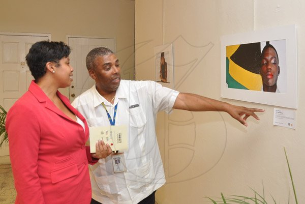 Jermaine Barnaby/Photographer
Leon Mitchell (right) JNBS Assistant General Manager makes some reference to the JN Foundation Resolution Project  best photo to Denise Gocoul at the Awards Ceremony at the Olympia Gallery- 202 Old Hope Road on Tuesday, July 15, 2014.