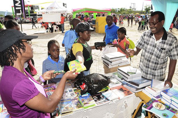 GladstoneTaylor Photographer
Left Beverley Hutchinson with Lenon Hardie  purchasing a pack of Crayons from Leroy Batiste while Janice Brown centre looks on  at Lime Skool Aid  Jam World Portmore St Catherine