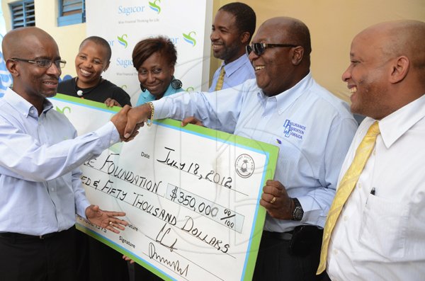 Rudolph Brown/Photographer
Willard Brown, (left) Vice President Risk Management , Actuary of Sagicor presents a cheque for $350,000.00 to Orville Johnson, (second right) Chairman of Best Care Foundation, while looking on from second left are H.E. Mathu Joyini, High Commissioner for the Republic of South Africa to Jamaica, Margaret Loney, Child Care Manager of Best Care, David Knight, Director of Best Care and Mark Chisholm, executive vice president Individual Insurance Division, Sagicor Life Jamaica, Sagicor also assist Best Care Foundation by donating 10 hospital bed mattresses to the Foundation in conjunction with the Nelson Mandela International Day at the Best Care Children Home in Kingston on Wednesday, July 18-2012