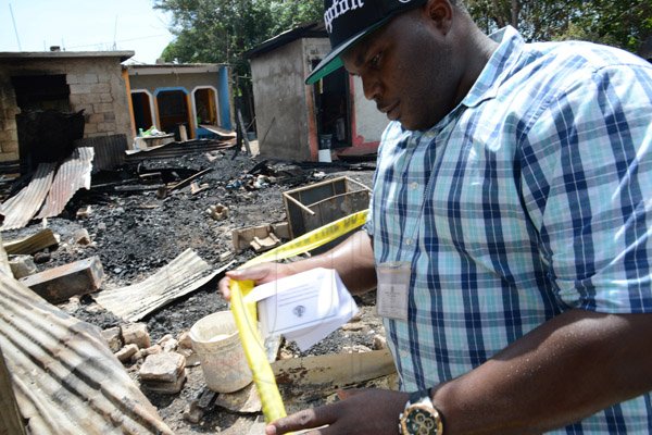 Rudolph Brown/PhotographerA police officer secure the crime scene after gunmen shoot up seven killing five including three children and set their home ablaze at Africa settlement in March Pen Community in Spanish Town on Sunday, October 9