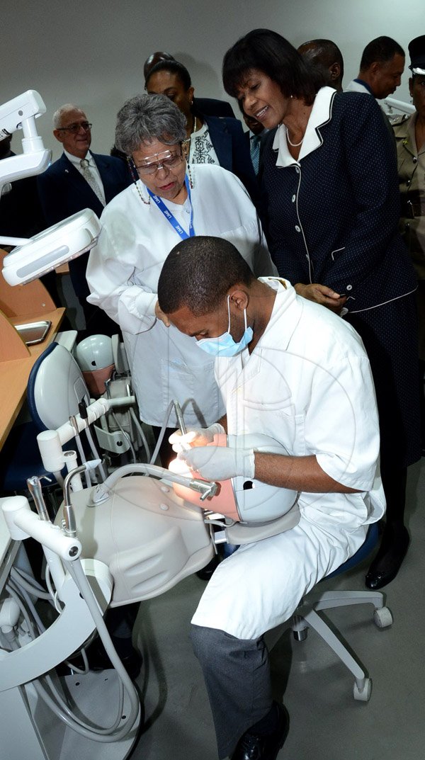 Winston Sill/Freelance Photographer
Prime Minister Portia Simpson-Miller opens UWI's   Faculty of  Medical Sciences' Teaching and Research Complex, and Launch of The UWI, Mona Dental Programme, held at West Road, UWI  Mona Campus, on Wednesday February 4 , 2015.  Here Dr. j. Suzanne Turpin-Mair (left), Senior Lecturer Operative Dentistry, explains what final year student Chafen Clarke (centre) is doing, to Prime Minister Portia Simpson-Miller (right) as she tours the Dental Lab.