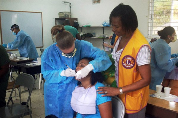 Photo by Valerie Dixon
Past President of the Lions Club of Mandeville, Jackie Foster (right) observes a volunteer from the Miami Dade College Medical Group providing dental care during a ecent wellness clinic in Manchester.