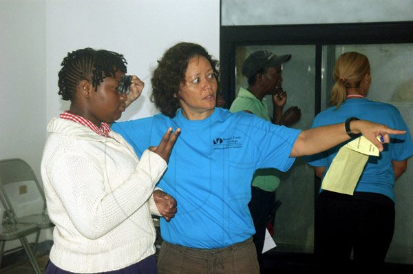 Photo by Valerie Dixon

Dr. Cindy Corke (right), Leader of the Medical Team from the Miami Dade College Medical Group tests the eye of a patient during a recent wellness clinic in Manchester, hosted by the Lions Club of Manchester.