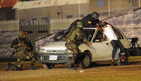 Ian Allen/Photographer
Members of the Jamaica Defence Force and Jamaica Constabulary Force apprehend a kidnapper in this hostage rescue simulation at the Jamaica Military Tattoo at Up Park Camp on Thursday June 28.