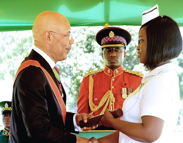 Lionel Rookwood/PhotographerDavia Ramano Tucker recieves The Badge Of Honour For Gallantry for her courageous efforts in rescuing patients from a fire at the Intensive Care Unit at the Bustamante Hospital for Children from Governor General Sir Patrick Allen at The National Honours and Awards held at King's House on Monday October16th,2017. *** Local Caption *** Lionel Rookwood/PhotographerFor Gallantry for her courageous efforts in rescuing patients from a fire at the Intensive Care Unit at the Bustamante Hospital for Children, in January, Davia Ramano Tucker receives The Badge Of Honour  from Governor General Sir Patrick Allen.
