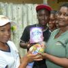 Ian Allen/Staff Photographer
Lacey Henry left, Promoter of Nestle Brands, presents a gift package to Jennifer Brevitt-James right during the Nestle "Knock at the Gate" promotions in the Stony Hills and Golden Spring area. Looking on are Shemar Miller and Verdie May Brevitt.
