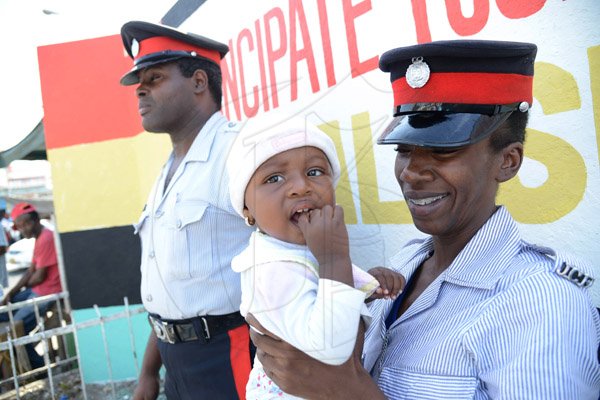 Rudolph Brown/Photographer
Woman Constable Daedre Blackstock plays with baby Amelia Simpson while constable Kemar Cohen looks on before the start of the West Kingston Peace March Theme: "Taking Back Our Communities" on Friday, August 1, 2014