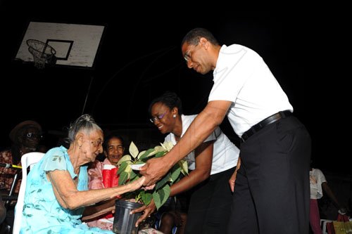 Ricardo Makyn/Staff Photographer
Jamaica Labour Party Leader The Hon Andrew Holness and Wife presents a Bag with goodies and a Plant  to  Olive Williams  whos is 101  Years Old at a Elderly Christmas Treat put on by the Member of Parliament at the Olympic Gardens Community Centre on Saturday 24.12.2011