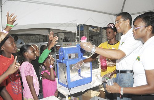 JIS/Photograph                                                                   Prime Minister Andrew Holness (second right), is assisted by his wife, Juliet, in handing out gifts to children from his West Central St. Andrew constituency whom he treated at the Olympic Gardens community centre on Olympic Way on Sunday, December 25.