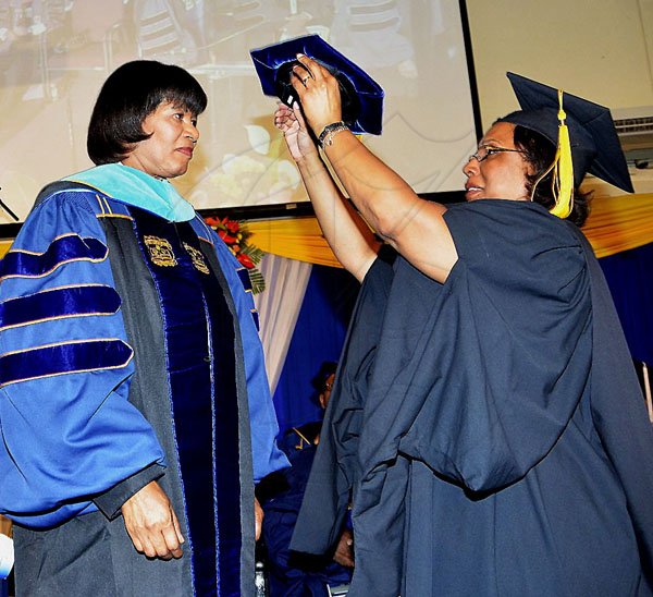 - ContributedPrime Minister Portia Simpson Miller (2nd right) is conferred with an Honorary Doctorate of Public Service by the Northern Caribbean University. Here the Prime Minister is robed by NCU's Registrar, Mrs. Avery Thompson at the University’s graduation ceremony on August 12.