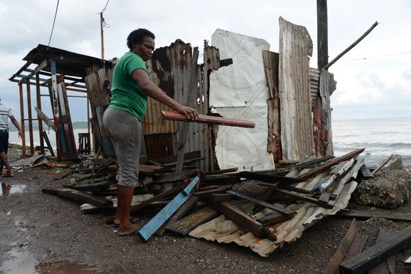 Ian Allen/Photographer A resident of Port Arthur Lane in Annotto Bay, St Mary, dismantles her house along the seaside board by board.